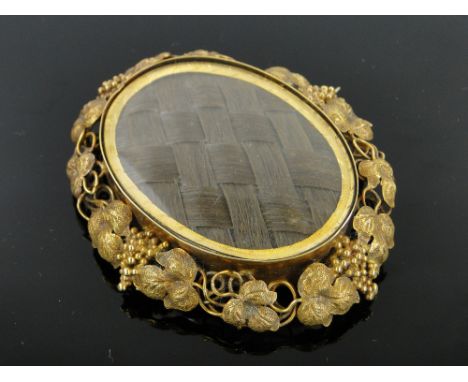 A 19th century unmarked gold mourning brooch,
with central hair panel in ornate vine surround, height 60mm.