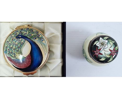 Moorcroft enamel circular trinket box decorated with peacock to lid and peacock feathers to the sides, 6cm diameter and a Moo