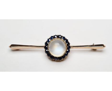 Gold-coloured metal, sapphire cluster and moonstone brooch centred by single cabochon moonstone having surround of sapphires,