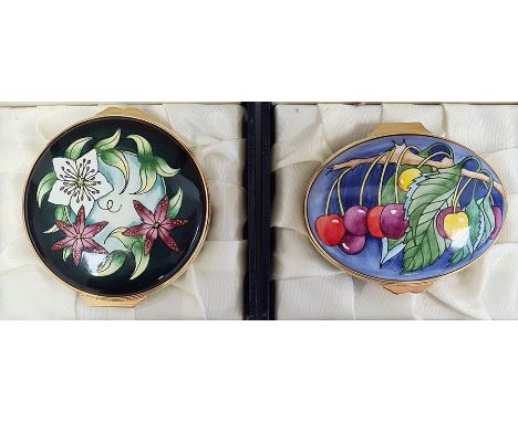 Moorcroft enamel patch box, oval and decorated with cherries on a blue ground, 6cm wide, boxed and another, circular, black a