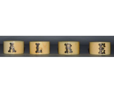 A SET OF FOUR IVORY NAPKIN RINGS with silver letters E. R. L. A.