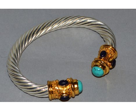 A STERLING SILVER BANGLE with lapis lazuli and turquoise decoration.