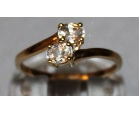 A TWO STONE ZIRCON CROSSOVER RING set in 9ct yellow gold.