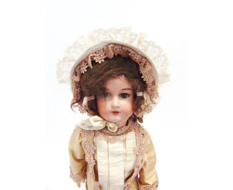 AN ARMAND MARSEILLE BISQUE SOCKET-HEAD DOLL with a brown wig, sleeping grey glass eyes, and an open mouth with four upper tee