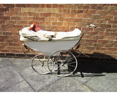 A DOLL'S PRAM early 20th century, the cream painted wooden body with a later folding hood and matching apron, and brass handl