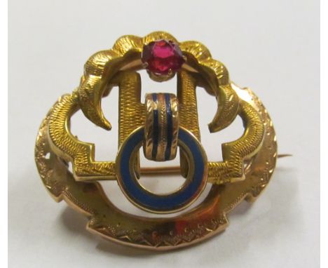 A gold coloured brooch enamel and red stone