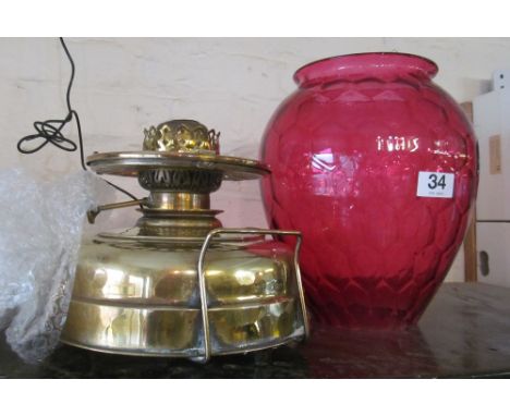 A brass paraffin lamp with large honeycomb cranberry shade