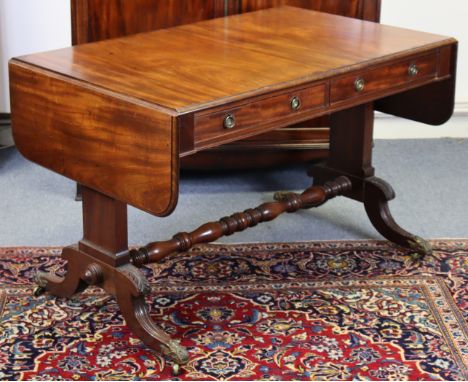 A regency mahogany sofa table with rounded corners to the drop leaves, fitted two frieze drawers with brass ring handles on c