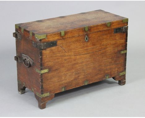 A late 19th century brass &amp; iron bound teak campaign trunk with hinged lid &amp; iron swing side handles, on ogee bracket