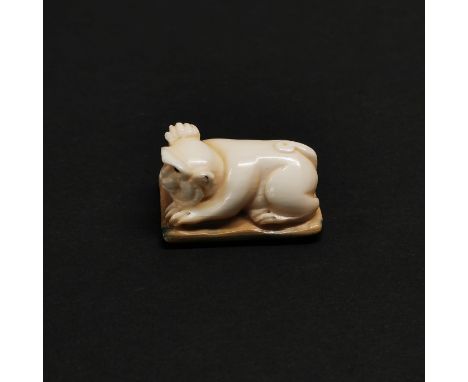 A carved fossilised mammoth tusk signed Netsuke of a monkey.