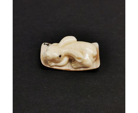 A carved fossilised mammoth tusk signed Netsuke of a rabbit.