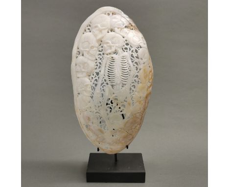 A hand carved river mussel mother of pearl shell with skeleton and skulls, polished; intricately carved and pierced by hand b