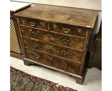 An early 18th Century walnut chest the quartered top feather banded over two short and three long graduated drawers to bracke