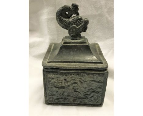 A 19th Century lead tobacco container, the lid with dolphin finial, the sides decorated in relief with hunting scenes togethe