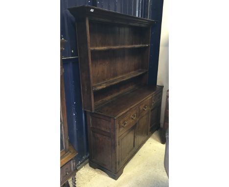 A 19th Century oak dresser the boarded two tier plate rack over three drawers and two cupboard doors raised on bracket feet
