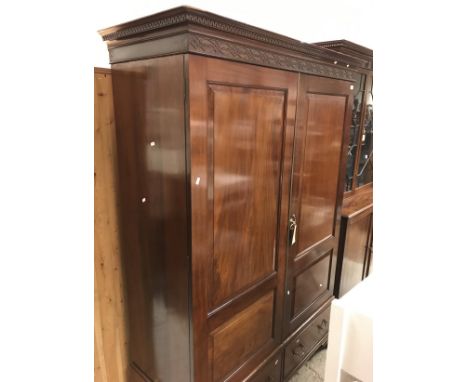 An Edwardian mahogany Jersey type wardrobe, the two panelled doors enclosing a hanging space over two drawers on ogee bracket