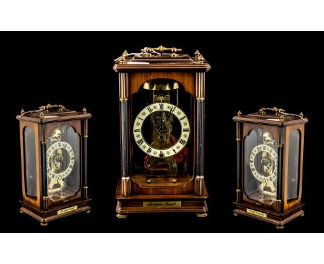 A Modern Skeleton Clock with Franz Hermle with a mahogany finish glass case with brass carrying handle. Height 12 inches. 