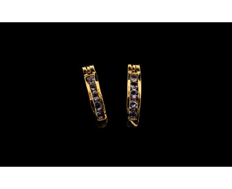 Tanzanite Huggy Hoop Earrings, each hoop, channel set with a row of round cut tanzanites, sits fairly close to the earlobe, t
