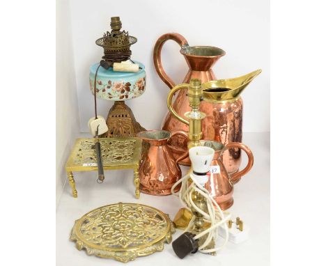 A selection of copper and brass ware, including: three copper harvest flagons; copper and brass jug; oil lamp table lamp with
