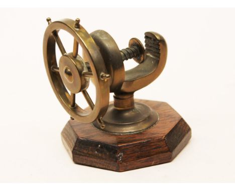A brass nut cracker in the form of a ship's wheel on oak base. H9.5cm. Condition - no damage, general wear only.