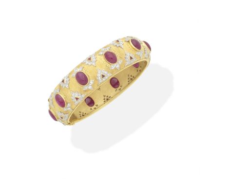 RUBY AND DIAMOND BANGLEThe hinged textured bangle set with repeating motifs of cabochon and triangular-cut rubies, and brilli