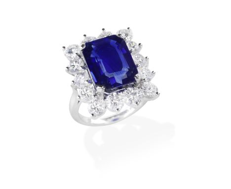 KUTCHINSKY: SAPPHIRE AND DIAMOND CLUSTER RING, 1979The step-cut sapphire, weighing 9.54 carats, within a surround of brillian