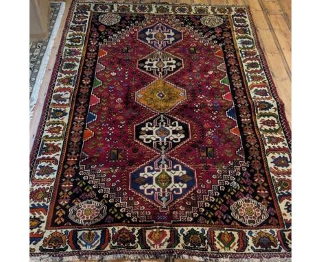 A Persian Qashgai carpet, with hooked medallions, on a red ground, within multiple borders, 245 x 175cm