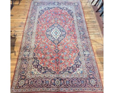 A Persian Kashan carpet, having a central medallion, on a red ground within multiple borders, 308 x 198cm