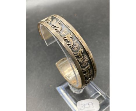 A silver torque bangle with wolves design