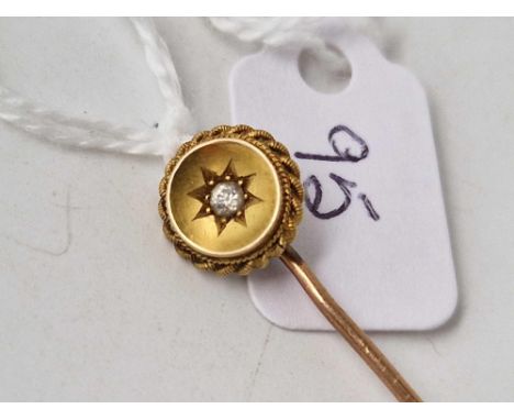 A gold topped stick pin, set with a diamond