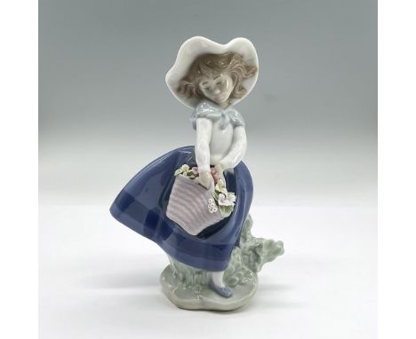 Glazed porcelain figure of a young girl in a wide brimmed hat, blue skirt and white top holding a basket of flowers. Lladro b