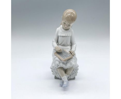 Glossy figure of a seated young girl in white with a small chalkboard. Nao backstamp. This item has its original box: 10"L x 