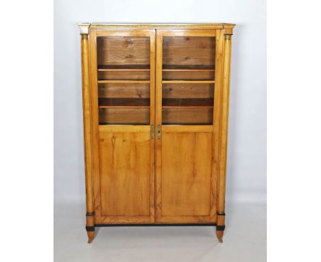 Biedermeier-Vitrine. Birke, auf Nadelholz furniert. Schlichter, zweitüriger Korpus (teilverglast) mit Halbsäulen, auf kurzen 