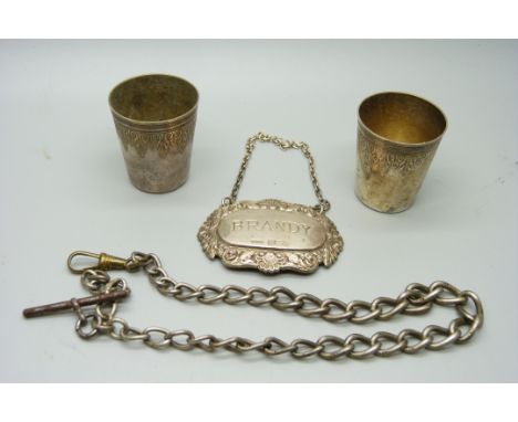 A silver brandy label, a silver Albert chain with base metal dog clip and T bar, and two white metal shot glasses 