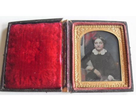 A hand-coloured Victorian daguerreotype three-quarter portrait of a lady with gilt arched mount in plush leather, 5 x 4 cm; t