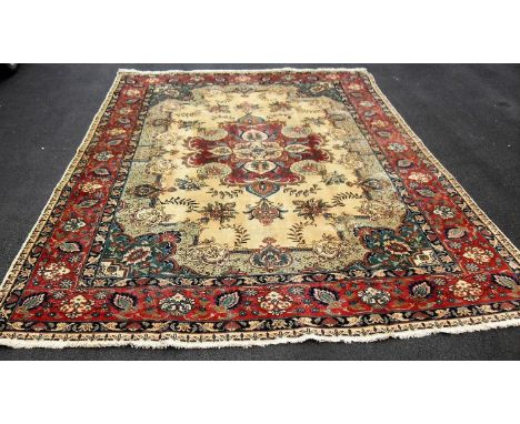 A Tabriz hand-knotted ivory-ground wool rug with multi-coloured floral and foliate designs, burgundy colour border and short 