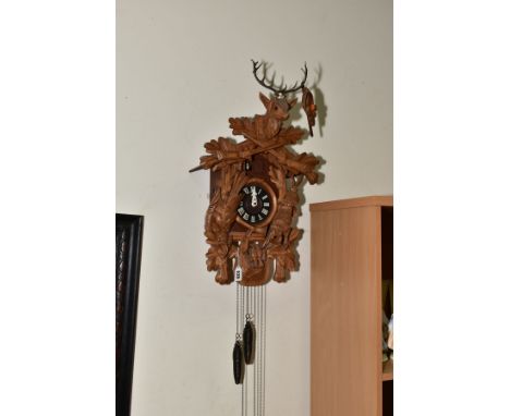 AN EARLY 20TH CENTURY BLACK FOREST CUCKOO CLOCK, with Stag's head carved to the leaf and gun pediment, with bird and hare fla