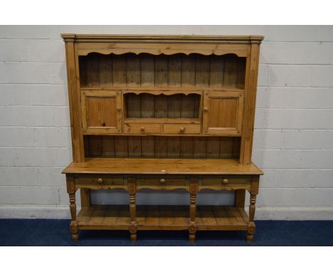 A VICTORIAN PINE DRESSER, the top double panelled doors, open shelves and two drawers above a base with three drawers, four t