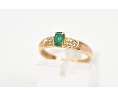 AN EMERALD AND DIAMOND RING, the yellow metal ring designed with a central oval cut emerald flanked with brilliant cut diamon