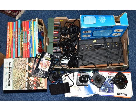 A TRAY CONTAINING VINTAGE GAMES CONSOLES, including an Atari CX-2600 with sixteen games, controllers and a Winthronics consol