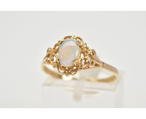 A 9CT GOLD OPAL RING, set with a central claw set oval cabochon opal, with an openwork scroll detail surround, to the plain p