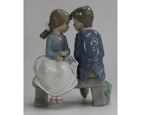 Nao figure of boy & girl seated in garden gazing into each other eyes, height 16.5cm