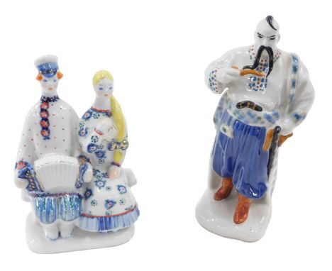 A Ukrainian figure of Taras Bulpa, 22cm high, and a figure of a couple sat on a bench with an accordion, 19cm high.