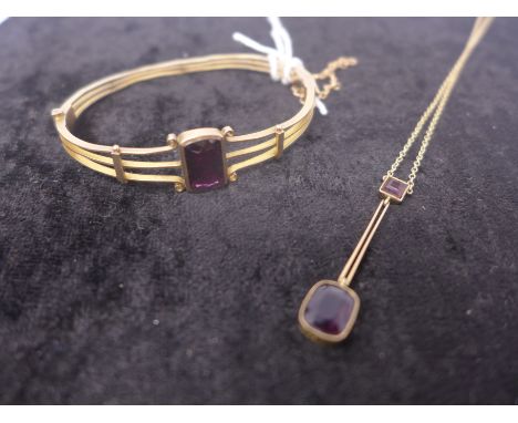 An Edwardian 9ct yellow gold bangle set with a rectangular faceted garnet and an Edwardian 9ct yellow gold amethyst drop pend