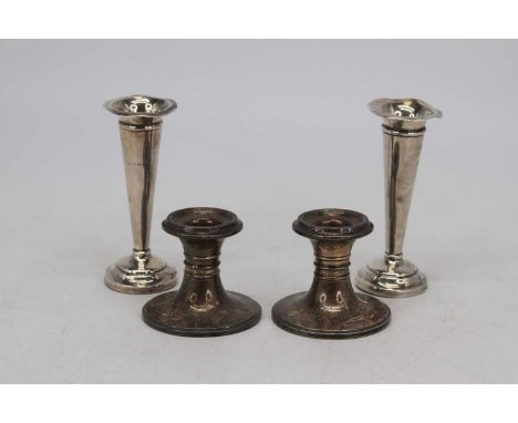A pair of George V dwarf filled silver candlesticks, Birmingham 1915, h.6cm; together with two silver spill vases, each havin