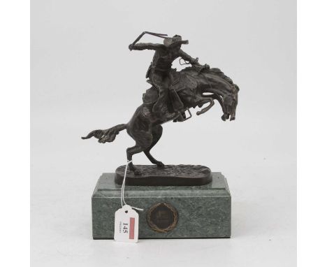 After Frederick Remington - a bronzed model of a cowboy on horseback, on naturalistic base, bearing signature and further gre