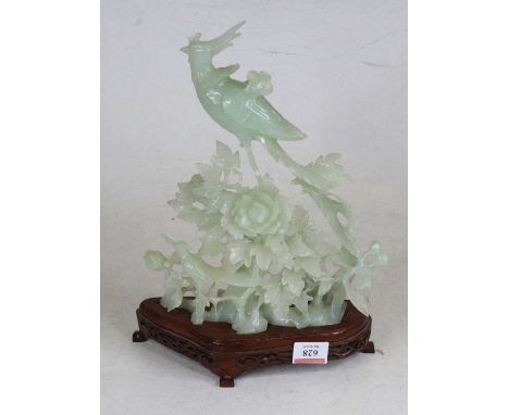 A Chinese carved and polished hardstone model of a phoenix perched upon a flower, standing upon further polished hardwood pli