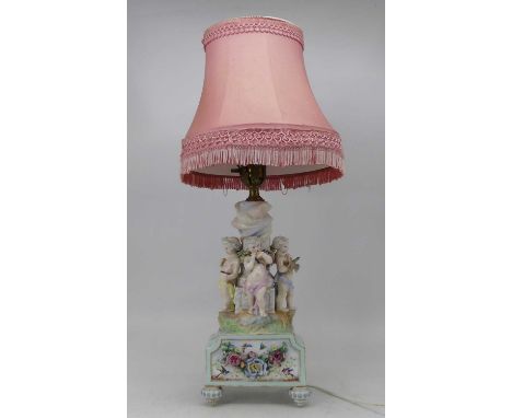 An early 20th century Dresden porcelain table lamp, the single gilt metal sconce on a fluted column surmounted by three cheru