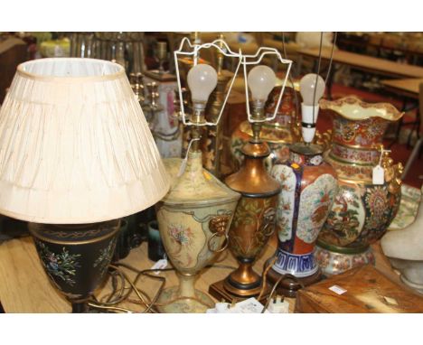 A toleware type table lamp on a black ground painted with an urn issuing flowers having pleated silk shade, height 58cm, toge