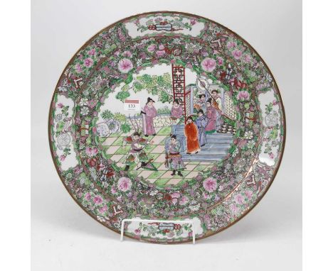 A large oriental charger, the central enamel decorated with various figures within a famille verte floral border, having six 